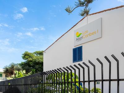 Edificio bianco con insegna e recinzione nera sotto cielo azzurro