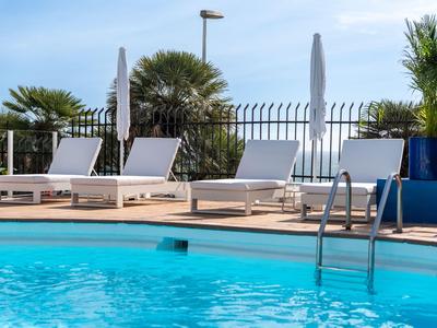 Empty pool area with lounge chairs and umbrellas on a sunny day.