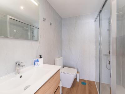 Bagno moderno con doccia, WC e lavabo in colori chiari.