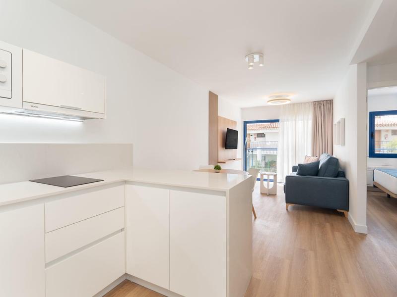 Zona giorno e cucina moderna e luminosa con pavimento in legno e accesso al balcone.