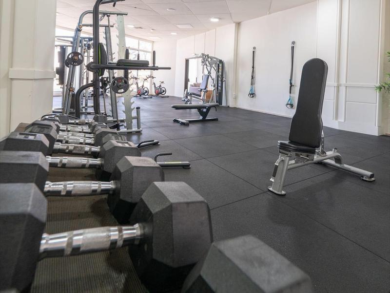 Gimnasio luminoso con pesas y equipos de entrenamiento en suelo negro en un hotel.