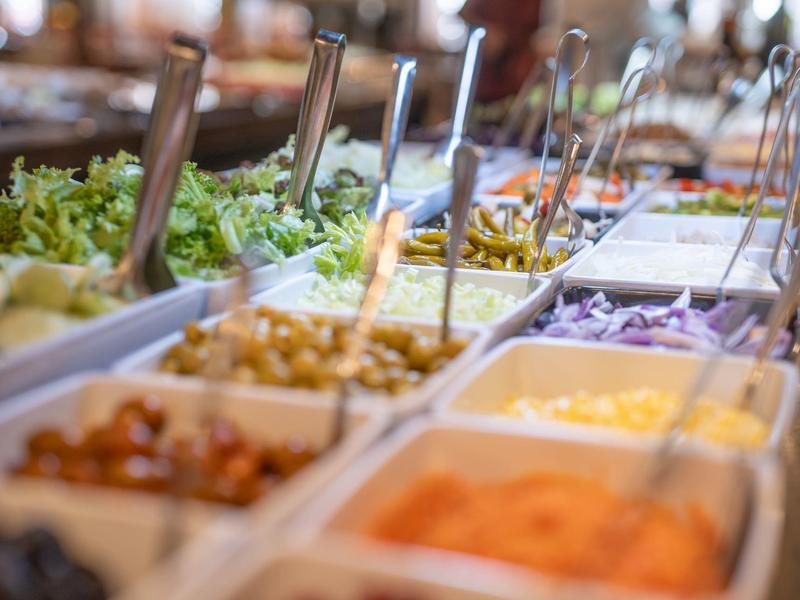 Buffet con diferentes ensaladas frescas e ingredientes en platos blancos