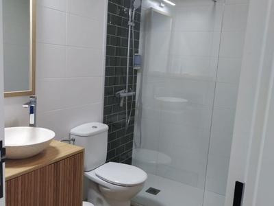 Moderne badkamer met douche, toilet, wastafel op houten kast en spiegel.