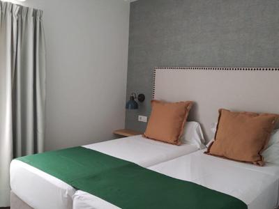 Moderne hotelkamer met twee eenpersoonsbedden, groene bedlopers en bruine kussens.