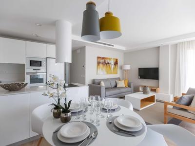 Salón y cocina modernas en una habitación de hotel con mesa de comedor y zona de estar.