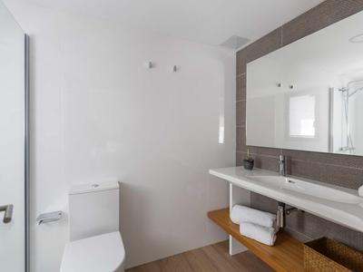 Baño moderno con inodoro, lavabo doble, toallas y espejo grande en pared marrón