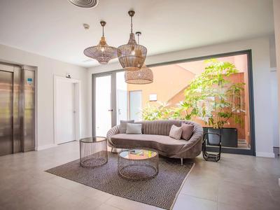 Lobby de hotel luminosa con muebles modernos, sofá, mesa de vidrio y grandes ventanas con vista exterior.