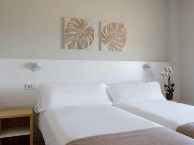 Piscina del hotel con tumbonas y sombrillas frente a un edificio de varios pisos con balcones.