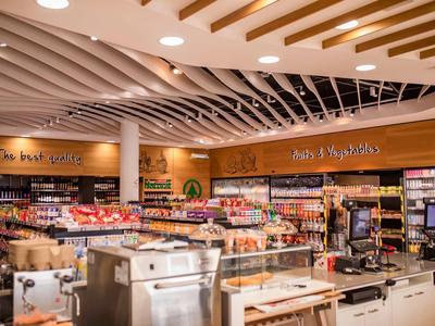 Área de compras moderna con alimentos y máquinas de café bajo luz brillante en el techo.