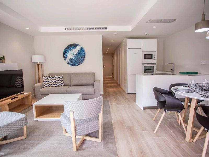 Sala luminosa con muebles modernos, cocina y comedor en un espacio abierto.