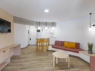 Moderner Wohnraum mit Holzboden, L-förmigem Sofa, Fernseher und Tresen mit Hockern.