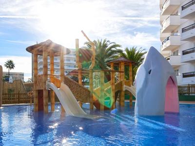 Children's water playground with slide and shark figure in a pool next to a hotel.