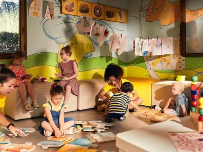 Preschool children playing and crafting together in a bright, colorful room.