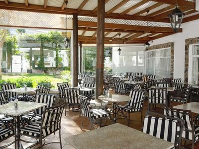 Covered terrace with black and white striped chairs and tables at a hotel.