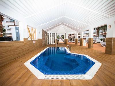 Indoor space with an octagonal hot tub and wooden flooring in a wellness area.
