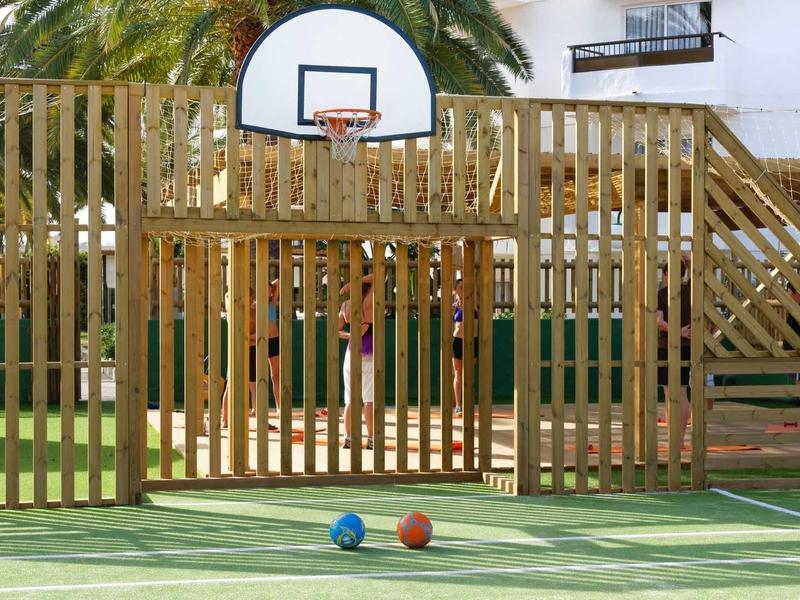 Outdoor basketball court with wooden fence and colorful balls on the ground.