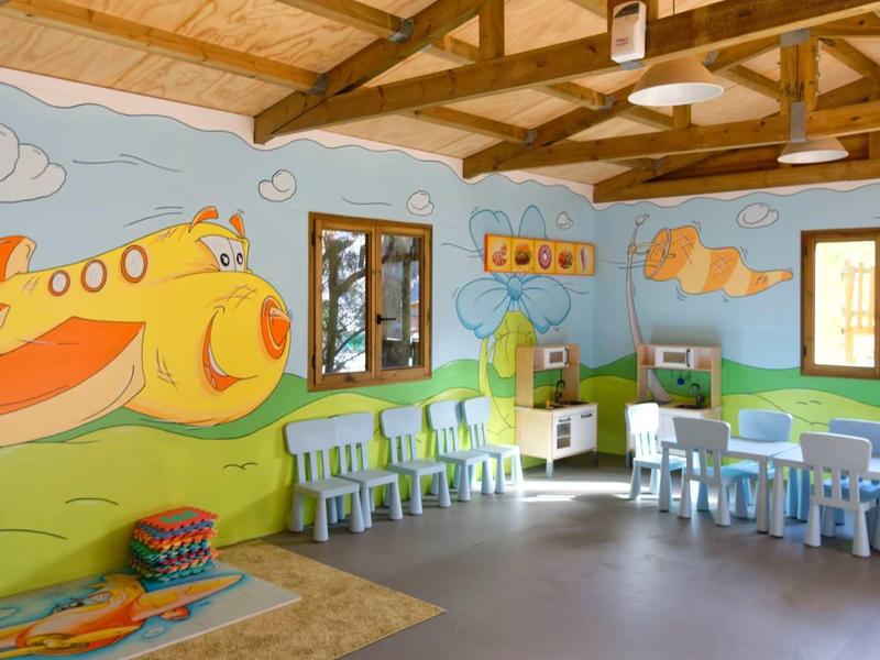 Children's room with colorful furniture, wall murals, and wooden beam ceiling in warm light.