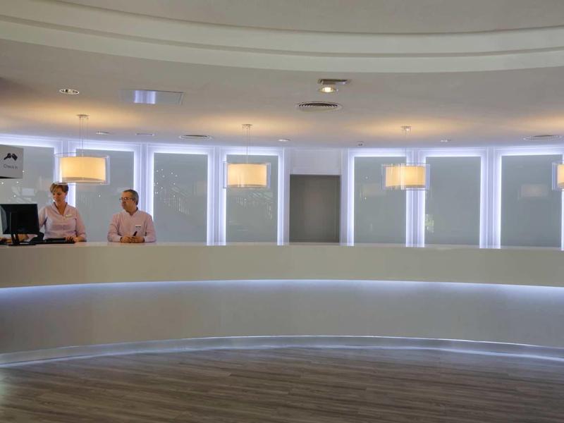 Modern hotel lobby reception with a long white counter and two staff members.