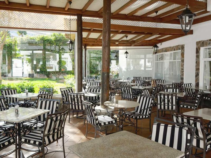 Covered terrace with black and white striped chairs and tables at a hotel.