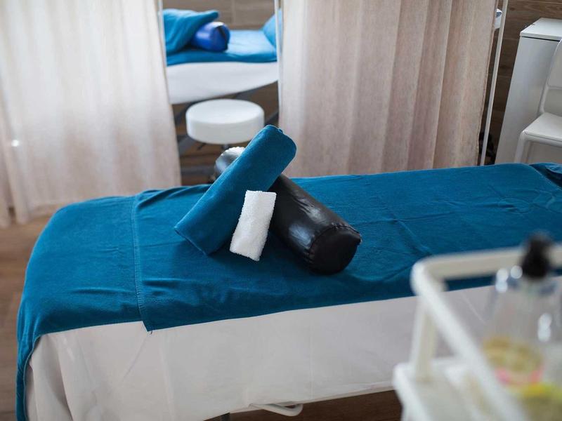 Massage table with blue cloth and rollers in a bright, calm room.