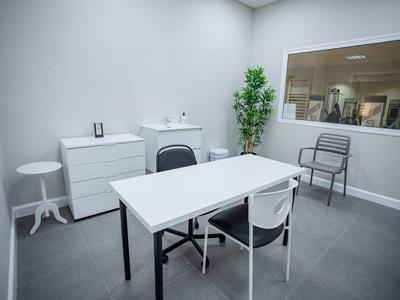 Moderner Besprechungsraum mit weißem Tisch, Stühlen, Kommode und großem Fenster zur Innenansicht.