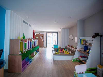 Helle Kinderspielecke mit bunten Regalen, Spielsachen und großem Fenster für viel Tageslicht.