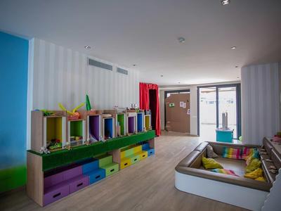 Kinderspielzimmer mit bunten Regalen, Sitzkissen und heller Holzbodenbeleuchtung.