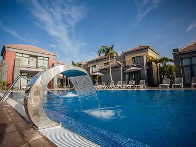 Hotelowy basen zewnętrzny z fontanną i leżakami pod słonecznym niebem