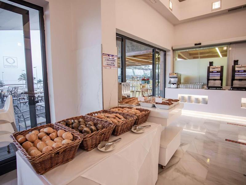 Buffetbereich mit Brotkörben, weißen Tischen, glattem Boden und großen Fenstern.