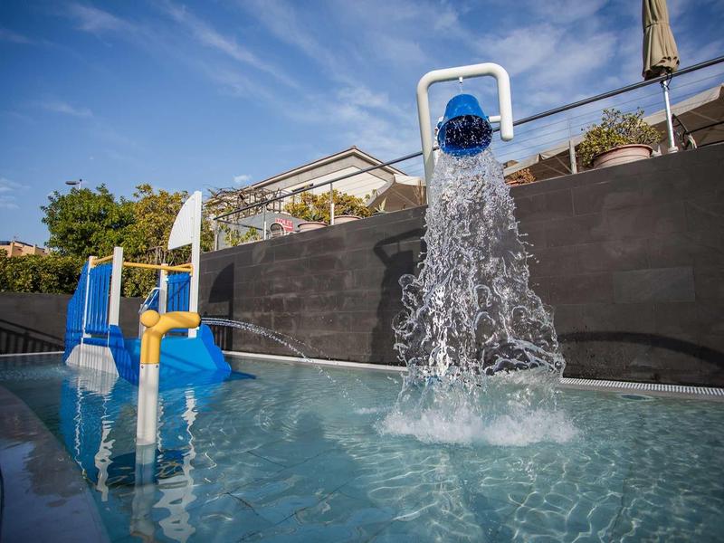 Wasserpark mit blauen Rutschen und einem Wasserspiel, das Wasser in den Pool schüttet.