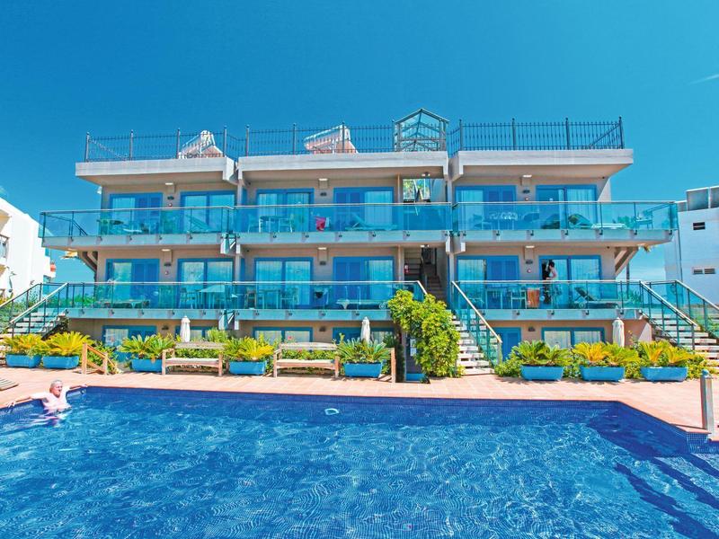 Modernes Hotel mit großem Pool und blauer Fassade bei klarem Himmel.