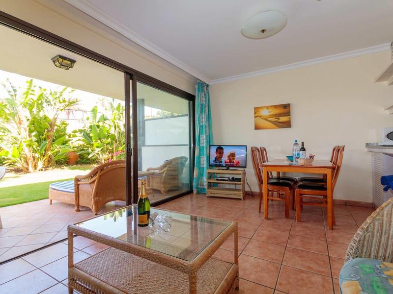 Salon lumineux avec porte vitrée donnant sur le jardin et coin repas avec table et chaises.