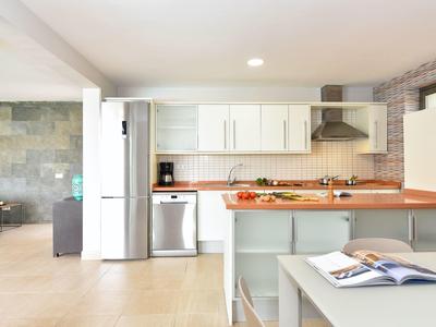 Helle Küche mit weißen Schränken, großer Insel, Holzanrichte und Edelstahlgeräten.