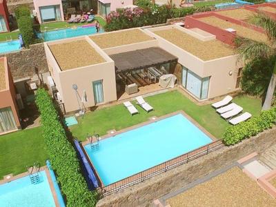 Moderner Garten mit rechteckigem Pool, Sonnenliegen, Rasen und angrenzenden Häusern.