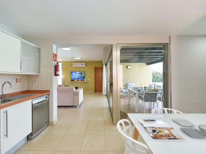 Moderne helle Küche mit weißen Schränken, Tisch mit Stühlen, Blick ins Wohnzimmer und auf Terrasse.