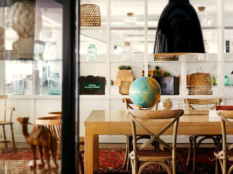 Moderner Arbeitsraum mit Holztisch, Stühlen, Globus und großen schwarzen Hängeleuchten.