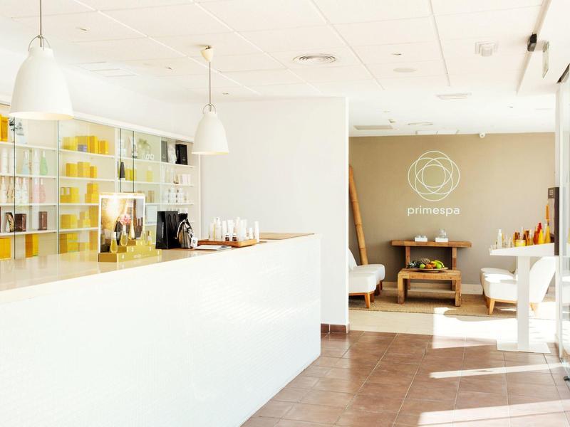 Heller, moderner Empfangsbereich mit weißer Theke, Holzregalen und Sitzbereich im Hintergrund.