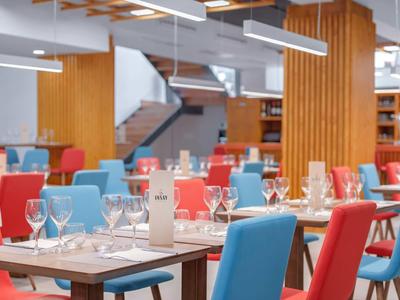 Salle de restaurant moderne avec chaises colorées et tables dressées.