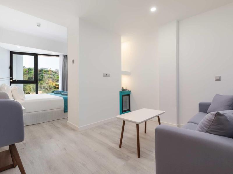 Salon moderne et chambre avec vue sur la nature, ambiance lumineuse et épurée.