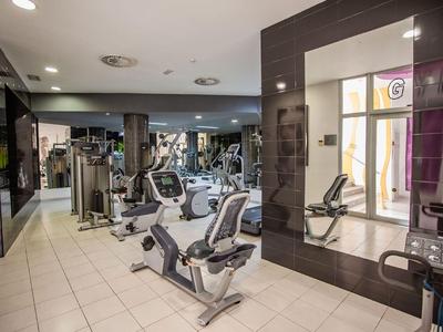 Modern gym room with various exercise equipment and large mirrors.