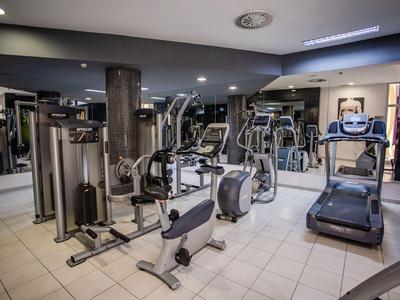 Modern gym with various workout machines and a large mirror wall.