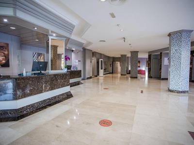 Jasna lobby hotelowa z marmurową podłogą, recepcją i wspierającą kolumną.