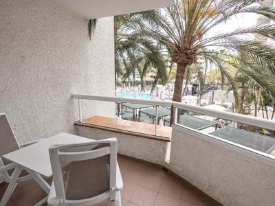 Balkon z białym stołem i krzesłami, widok na palmy i ulice