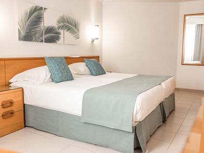 Nowoczesny pokój hotelowy z łóżkiem podwójnym i niebiesko-zielonymi akcentami.