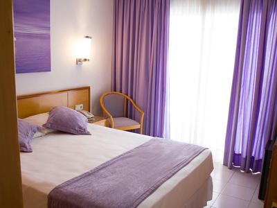 Pokój hotelowy z podwójnym łóżkiem, fioletowymi zasłonami i pasującymi poduszkami na spokojny pobyt.