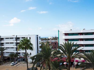 Widok na budynki hotelowe z palmami i niebieskim niebem w tle.