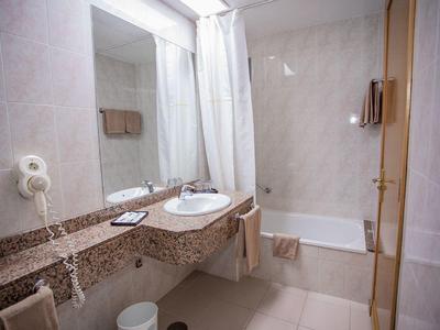 Nowoczesna łazienka hotelowa z dużym lustrem, umywalką, wanną i suszarką do włosów.