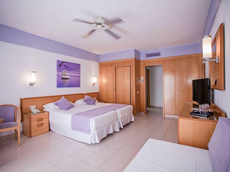 Jasny pokój hotelowy z dwoma pojedynczymi łóżkami, biurkiem i telewizorem.