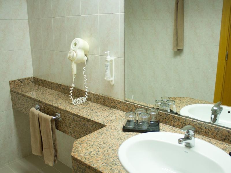 Nowoczesna łazienka z granitową umywalką, ręcznikami i suszarką do włosów na ścianie.