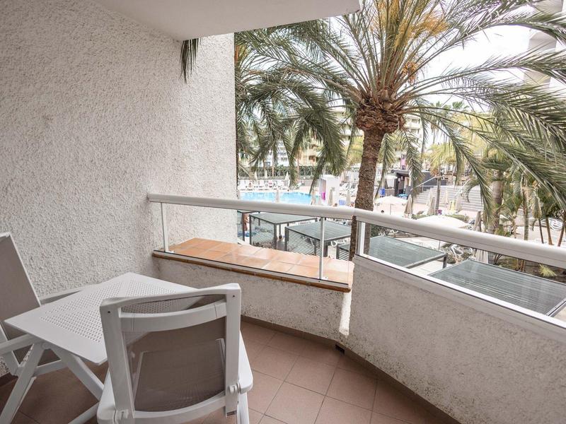 Balkon z białym stołem i krzesłami, widok na palmy i ulice